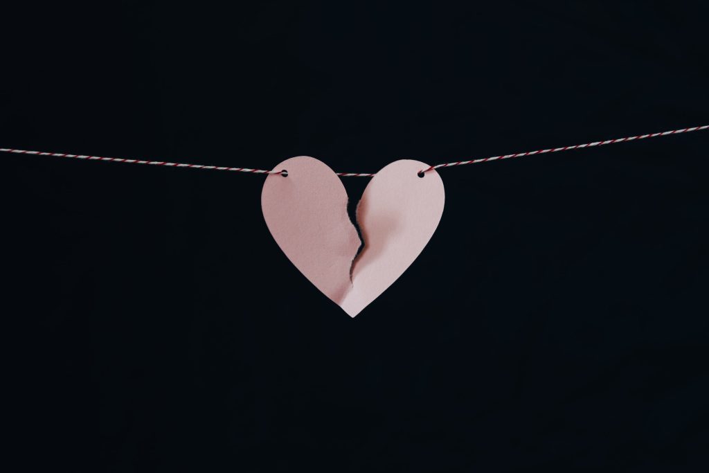 in article about past relationships, an image of a paper heart tearing in half on a black background