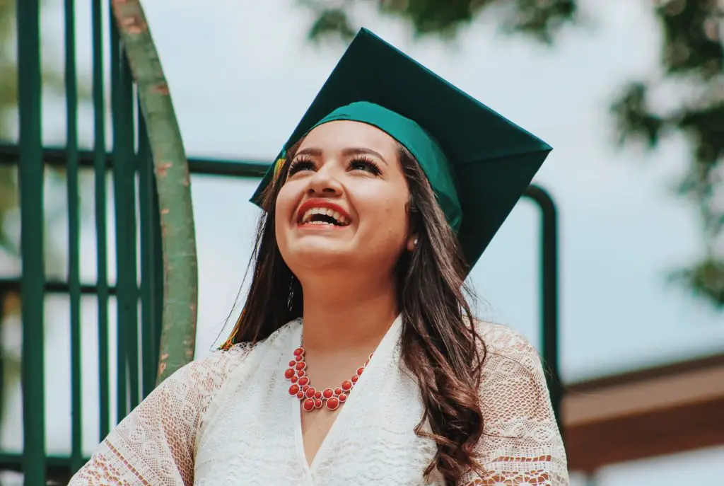 In an article about nontraditional college students a woman in a white dress and green graduation cap smiling.
