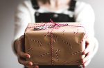 In an article about cheap gifts for broke college students, a girl holds out a present in front of her.