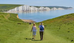 in an article about saving for retirement during inflation, an older couple hikes in front of a lake.