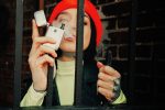 A woman in a red beret vaping behind a gate