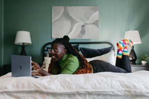 In an article about video essays, a person lies on their bed with an open laptop.
