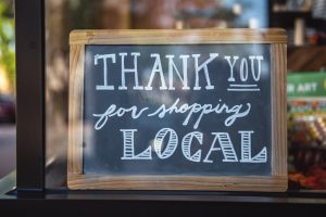 In an article about social media and small businesses, a chalkboard in a shop window reads 'Thank you for shopping local.'