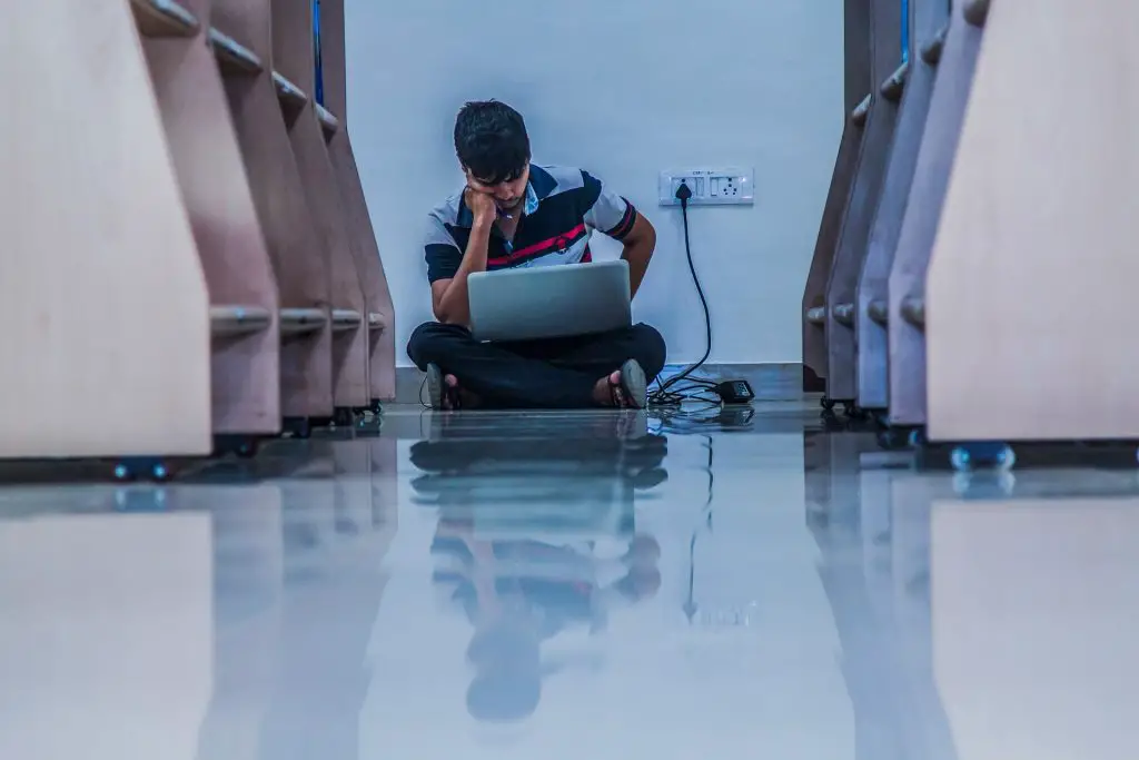 In an article about taking a gap year, a student sits on the floor at school while staring at his laptop.