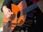 In an article about traditional Mexican music, a guitar player holds a classical guitar up close to strum it.