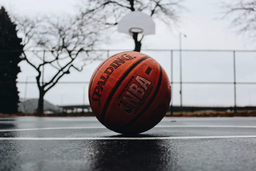 In an article about corruption in the Alabama basketball team, a basketball sits on a damp basketball court.