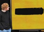 In an article about Ed Sheeran, the pop singer looks at a large screen displaying the cover of his latest album.