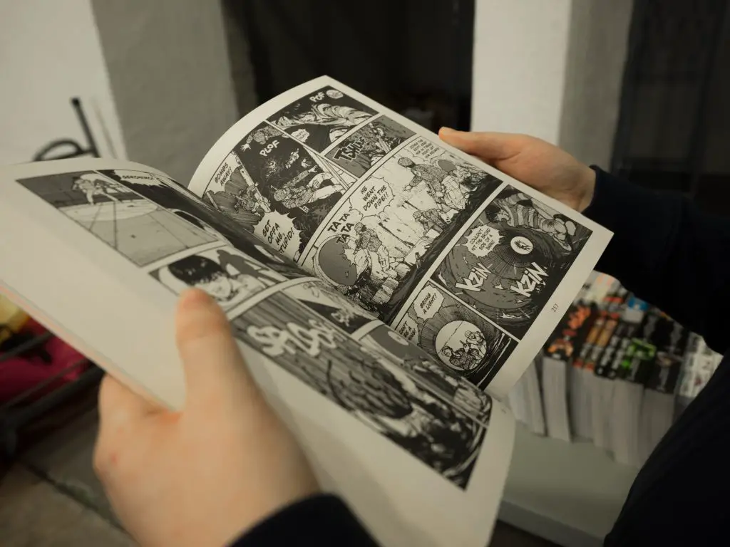 In an article about comic books and manga, a person reads a volume of manga.