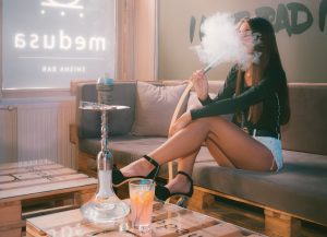 Photo of girl on a couch smoking a hookah pipe.