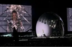 The big screens behind the stage show Beyonce dressed in a bright metallic outfit with a shining metal sun-shape behind her like a halo.