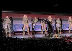 Beyonce and her daughter Blue Ivy are reflected three times across a giant screen, both dressed in camouflage outfits.