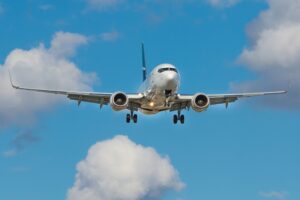 In an article about surviving a long-haul flight, an airplane flies against a blue sky.