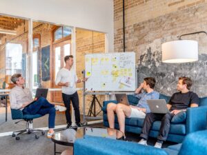 People in office standing next to white board