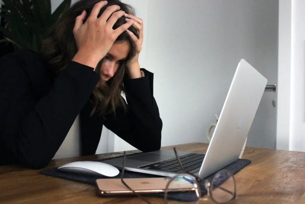 In a story about stress woman with hands on her head in front of a computer.