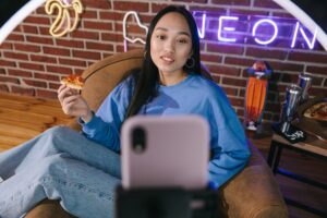 In an article about content creators woman in front of her cell phone recording herself