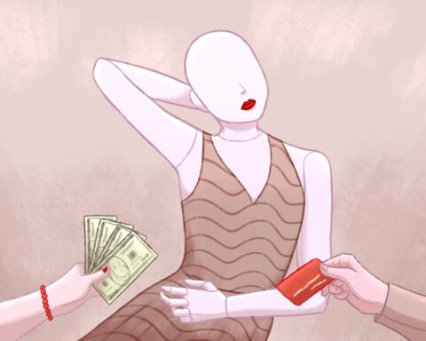 In an article about the ric, white gaze that U.S. Vogue implores, a mannequin with pale skin and red lips stands with one arm behind their head and one arm across their belly. An off-screen figure's hand holds cash while another off-screen figure's hand holds a red credit card.