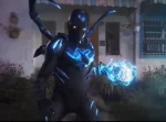 In an article about 'Blue Beetle,' superhero Jaime Reyes strikes a defiant and protective stance in front of his family home.