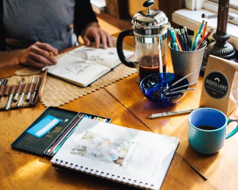 In an article about active learning, someone sits with an open journal, craft supplies, and a french press pitcher with coffee.