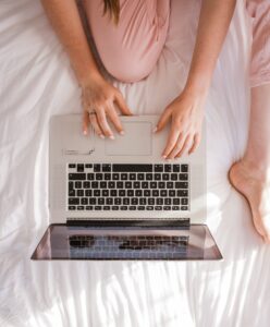 In an article about student essays woman on bed with a laptop