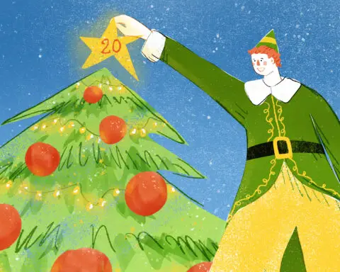 In an article about "Elf" 20 year anniversary, a man with orange hair and green coat and yellow stockings places a glowing yellow star with the number "20" on it" atop a green Christmas tree with red ornaments and bright yellow lights.