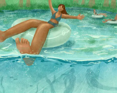For an article on the Weeki Wachee park, a woman in a bathing suit on a floating device while in water while mermaids swim below her.