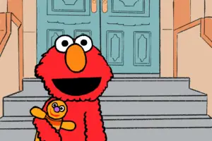 Elmo stands in front of a grey staircase, flanked by brown walls, leading up to a set of blue doors. He is hugging an orange dolls close to his chest as he gives the audience a smile; the special kind, which is warm, and reassuring and promises you that everything will turn out all right in the end.