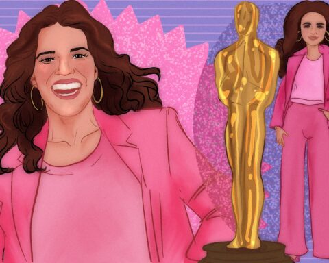 A woman with brown hair in a pink coat beams with a bright smile against a pink and purple background. To her right, a golden statue leans against a smiling doll in the woman's image. Said doll holds its hand in its pocket as it cocks out its hip, standing in a firm yet casual pose.