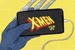A hand in a blue glove with metal claws poking holds an iPhone against a yellow background. The phone is displaying a logo cast in bold yellow and red font -- most likely the newest piece of X-Men media grabbing his attention -- while a white cord is plugged into some unseen outlet offstage, presumably to keep the phone charged and running as he watches.