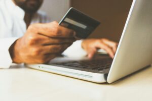 Man holding a credit card next to laptop