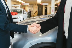 Shaking hands in front of a car